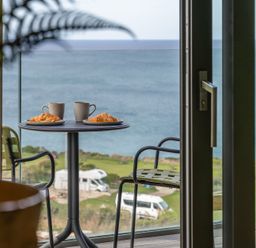 A table with mugs and croissants on a balcony with a sea view at tbc in St. Ives