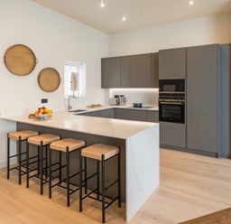 A kitchen with a countertop and bar stools at The Old Barn in St. Ives