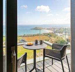 A balcony with a table and chairs overlooking the sea at Hidden 9 – Grand Bay Suite Hot Tub, St Ive