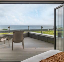 A bedroom with a view of the ocean and a chair at tbc in St. Ives