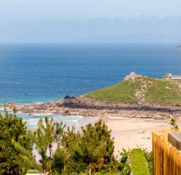 A view of the beach and hill with lighthouse at Hidden 12- Hot Tub Terrace St Ives