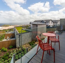 An outdoor area with a deck and chairs at Hidden 10- Godrevy View St Ives