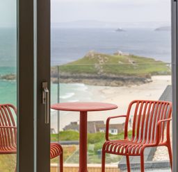 A balcony with a table and chairs overlooking the beach at Hidden 10- Godrevy View, St Ives