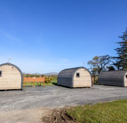 Three wooden pods with a sign in between at Bron Eifion Pod 1 Criccieth