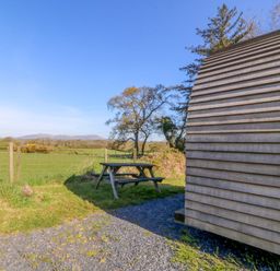 An outdoor area with a wooden pod and picnic table at Bron Eifion Pod 1 Criccieth