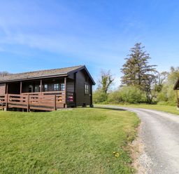 A cabin with porch beside a gravel road at Lodge 2 - Bron Eifion