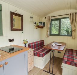 A dining area with a table and seating at The Three Spaniels Shepherds Hut in Cwrtnewydd near Llanybydder