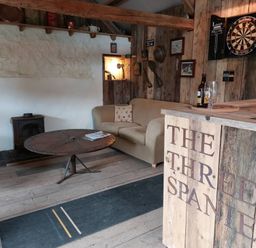 A snug with a sofa and a wood stove at The Three Spaniels Shepherds Hut in Lampeter