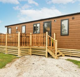 A mobile home with a wooden deck and stairs at Hedgehog Lodge Carnforth