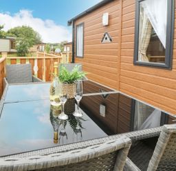 An outdoor seating area with a table and chairs at Hedgehog Lodge in Carnforth