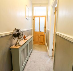 A hallway with a globe on a table and a wooden door at 17 Fairfield Road