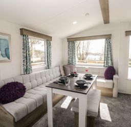 A living room with a sofa and dining table at Standard Caravan at Three Lochs Holiday Park, Newton Stewart