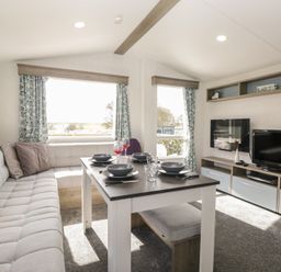 A living room with a dining table and sofa at Standard Caravan at Three Lochs Holiday Park in Newton Stewart