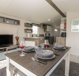 A dining area with a table set for meals at Standard Caravan at Three Lochs Holiday Park Newton Stewart