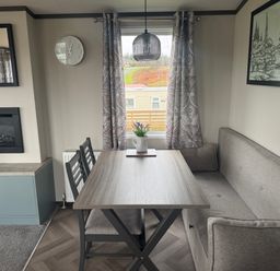 A dining room with a gray table and sofa at Lochwood Platinum Superior at Three Lochs Holiday Park Newton Stewart