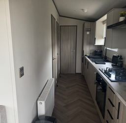 A kitchen with cabinets and appliances at Lochwood Platinum Superior at Three Lochs Holiday Park Newton Stewart