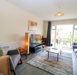 A living room with seating and a television at The Mill House Gardens