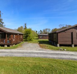 Three cabins with a pathway in front at Lodge 5 - Bron Eifion in Criccieth