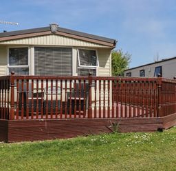 A mobile home with a deck and grass at Beech Lodge in Wadebridge