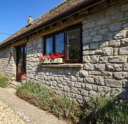 A stone cottage with flowers on the windowsill at Dunvant in Swanage