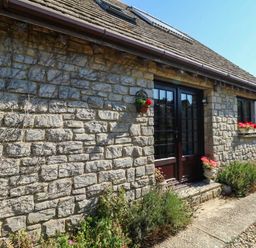 A stone wall with flowers and a pathway at Dunvant in Swanage