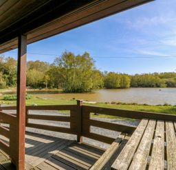 A deck with a view of a lake and trees at Lodge 6 - Sleep 4 - Twin and Double, Criccieth