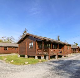 A row of wooden cabins along a gravel road at Lodge 6 - Sleep 4 - Twin and Double in Criccieth