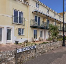 A row of properties with balconies and a sign at 2 Lyme Mews in Seaton