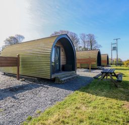 An outdoor view of camping pods with a picnic table at Bron Eifion Pod 2 in Criccieth