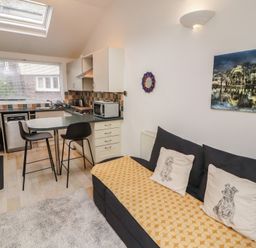 A kitchen area with a couch and bar stools at Juniper Hayloft in Ambleside