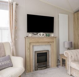 A living room with a television and a fireplace at Swan Haven in Grange-Over-Sands