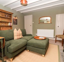A snug with a sofa and bookshelf at The Cook’s Cottage in Malton