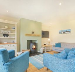 A living room with a fireplace and seating area at Beach Walk in Chathill