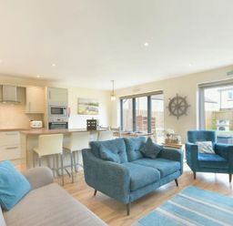 A living room with a sofa and kitchen area at Beach Walk in Chathill