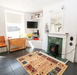 A living room with a fireplace a TV a wooden chair and a drop leaf table at Bridge Cottage Haltwhistle near Hadrians Wall