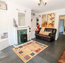 A living room with two brown leather sofas a fireplace with a mirror above a colorful rug and a wall painting at Bridge Cottage Haltwhistle near Hadrians Wall