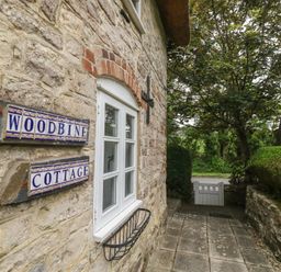 Exterior view of Woodbine Cottage with stone wall and pathway in Weymouth