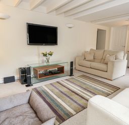 A living room with a television and sofa at Woodbine Cottage in Weymouth