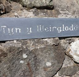 A sign on a stone wall at Tyn Y Weirglodd in Deiniolen