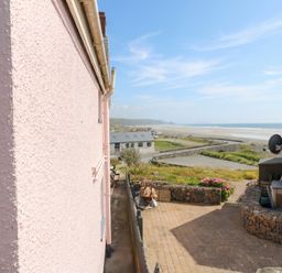 An outdoor area with a pink wall and a view of the sea at Newgale Cottage in Newgale