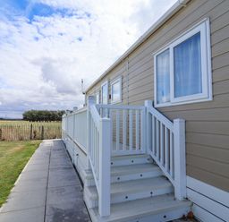 A caravan exterior with steps and grass at Caravan i35 in Towyn