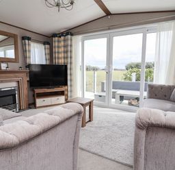 A living room with a television and fireplace at Caravan i35 Towyn