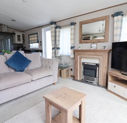 A living room with a sofa and television at Caravan i35 Towyn