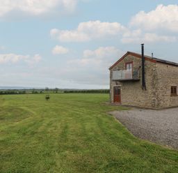 An outdoor area with a stone building and grass at The Gallops in Barry