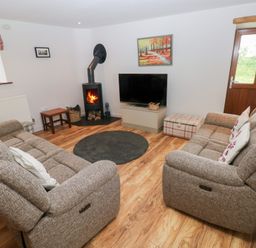 A living room with a sofa, rug, and television at The Gallops in Barry