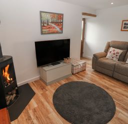 A living room with a fireplace and TV at The Gallops in Barry