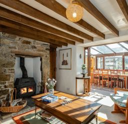 A living room with a fireplace and wooden table at Trehaverock Cottage in St. Endellion near Port Isaac