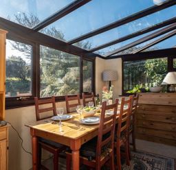 A dining table with chairs and a kitchen cabinet at Trehaverock Cottage St. Endellion near Port Isaac