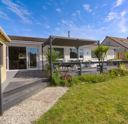 An outdoor area with a house, deck, table, and plants at Agan Paradhis in Quintrell Downs