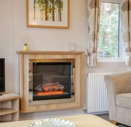 A living room with a fireplace and television at Bingos Cabin in Holt